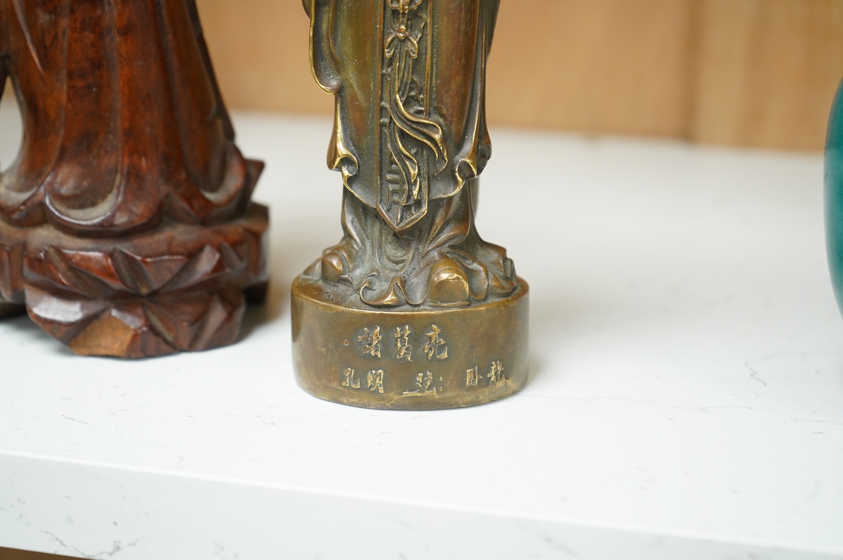 A bronzed Chinese figure of Qianlong, a carved bamboo brush pot and a hardwood figure, largest 20cm high